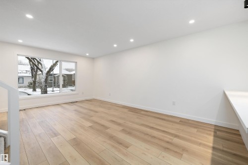 Bright interior space featuring light wood-finish flooring, recessed lighting, and a large picture window - 11918 93 Street, Edmonton, AB - Indoor Photo Showing Other Room