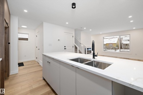 Kitchen island featuring a dual basin stainless steel sink with a matte black faucet, and a light-toned countertop - 11918 93 Street, Edmonton, AB - Indoor Photo Showing Kitchen With Double Sink