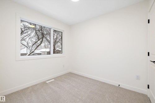 Neutral wall paint with crisp white trim, light gray carpeting, and a window with a white frame - 11918 93 Street, Edmonton, AB - Indoor Photo Showing Other Room