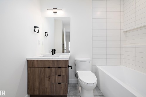 Modern bathroom featuring a wood-finish vanity with a white countertop and rectangular undermount sink - 11918 93 Street, Edmonton, AB - Indoor Photo Showing Bathroom
