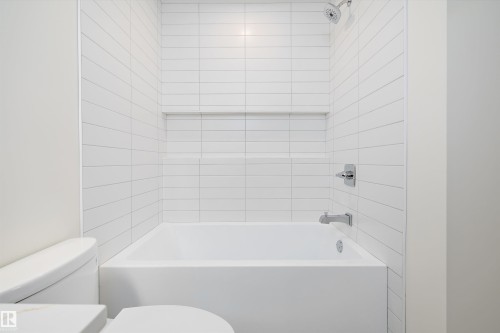 Contemporary bathtub with white subway tile surround, chrome fixtures, and an integrated shower niche - 11918 93 Street, Edmonton, AB - Indoor Photo Showing Bathroom