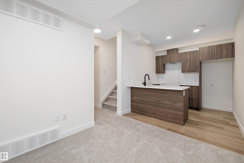 Compact kitchen featuring wood-finish cabinetry, white countertop, and white subway tile backsplash - 11918 93 Street, Edmonton, AB - Indoor Photo Showing Kitchen