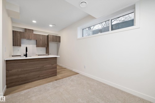 Compact kitchenette featuring wood-finish cabinetry, white subway tile backsplash, and a white countertop - 11918 93 Street, Edmonton, AB - Indoor
