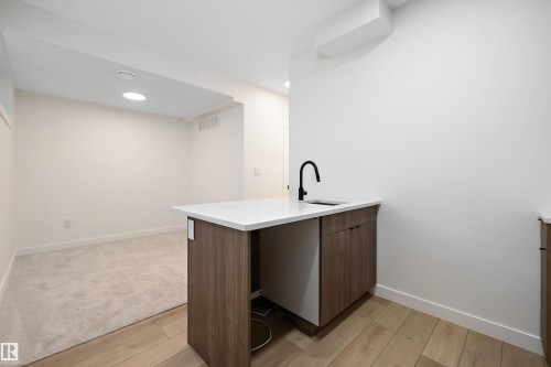 Built-in cabinetry with wood-finish doors, white countertop, and a matte black faucet - 11918 93 Street, Edmonton, AB - Indoor