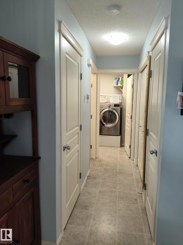 Hallway featuring light blue walls and gray square tile flooring - 59 Rue Monette, Beaumont, AB - Indoor Photo Showing Laundry Room