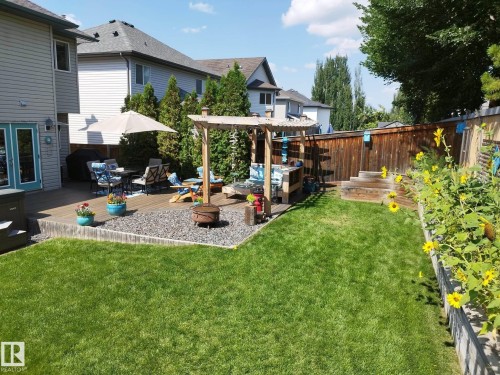 Expansive backyard featuring a manicured lawn, multi-level wood-finish decking, and a raised garden bed - 59 Rue Monette, Beaumont, AB - Outdoor With Deck Patio Veranda With Exterior