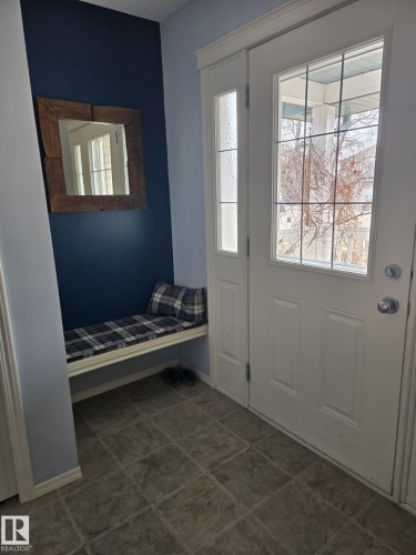Entryway featuring a white door with multiple glass lites, coordinating sidelite, and a built-in bench - 59 Rue Monette, Beaumont, AB - Indoor