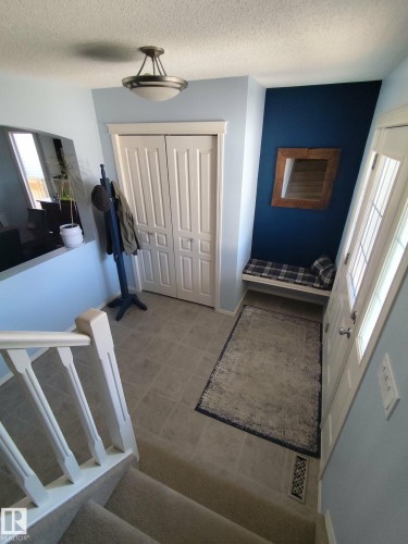 Foyer entryway featuring neutral-toned tile flooring, a built-in bench, and a dual-door closet - 59 Rue Monette, Beaumont, AB - Indoor Photo Showing Other Room