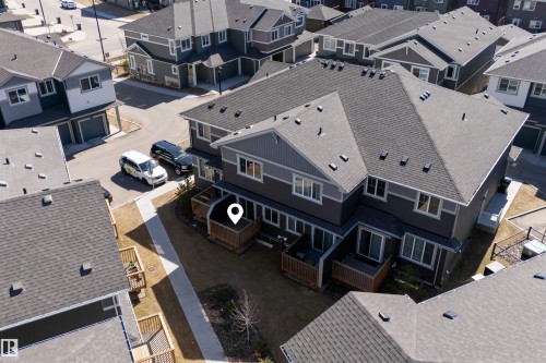 Modern multi-unit residence featuring a dark gray exterior with lighter gray accents, multiple private patios with wooden railings, and a shingled roof - 51 603 Orchards Boulevard Sw, Edmonton, AB - Outdoor