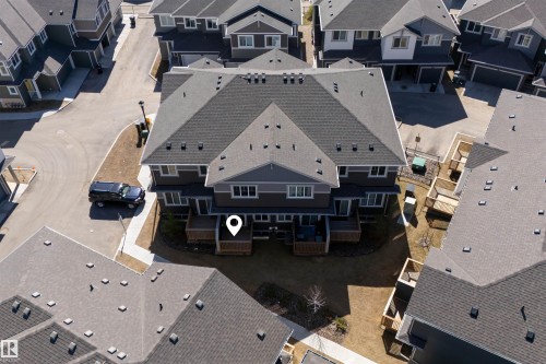 New construction townhome featuring a multi-level gray and white facade, private rear decks, a common green space, paved access roads, and multiple window placements - 51 603 Orchards Boulevard Sw, Edmonton, AB - Outdoor With Facade