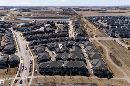 Aerial overview of a residential neighborhood featuring multiple housing units, paved streets, and a pedestrian pathway system - 51 603 Orchards Boulevard Sw, Edmonton, AB - Outdoor With View