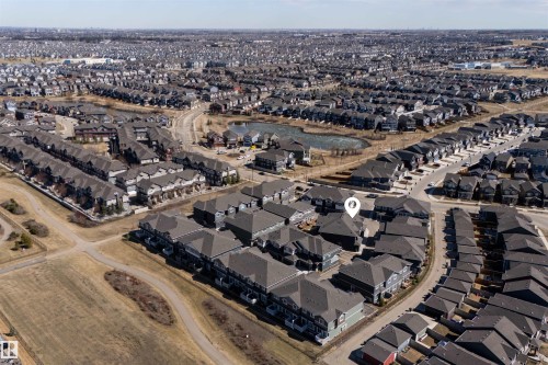 Aerial perspective showcasing the residential community with a central pond and established infrastructure - 51 603 Orchards Boulevard Sw, Edmonton, AB - Outdoor With View