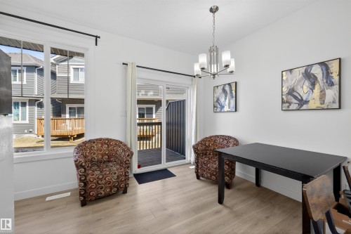 Bright interior space featuring light wood-finish flooring, white walls, and a contemporary chandelier - 51 603 Orchards Boulevard Sw, Edmonton, AB - Indoor