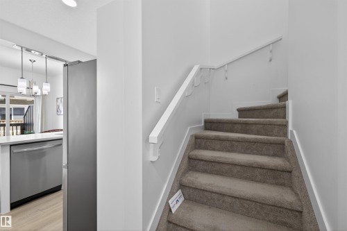 Carpeted staircase with white handrail - 51 603 Orchards Boulevard Sw, Edmonton, AB - Indoor Photo Showing Other Room
