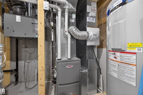 Utility area featuring a Lennox furnace, humidifier, and a hot water heater - 51 603 Orchards Boulevard Sw, Edmonton, AB - Indoor Photo Showing Basement