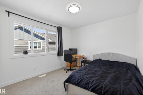 Bright room with a large multi-pane window, flush-mount ceiling light, and light-toned carpet - 51 603 Orchards Boulevard Sw, Edmonton, AB - Indoor Photo Showing Bedroom