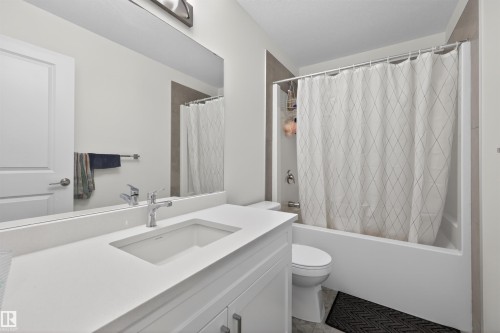 Bathroom featuring a white vanity with an integrated sink, polished chrome faucet, and a large wall-mounted mirror - 51 603 Orchards Boulevard Sw, Edmonton, AB - Indoor Photo Showing Bathroom