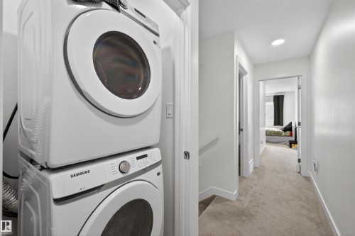 Hallway with light-colored carpeting and white baseboards - 51 603 Orchards Boulevard Sw, Edmonton, AB - Indoor Photo Showing Laundry Room