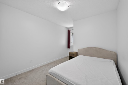Bedroom featuring light grey carpeting, white walls, a flush-mount ceiling light, and a window with horizontal blinds - 51 603 Orchards Boulevard Sw, Edmonton, AB - Indoor Photo Showing Bedroom