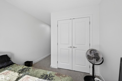 White interior walls with white baseboards and neutral carpet flooring - 51 603 Orchards Boulevard Sw, Edmonton, AB - Indoor Photo Showing Bedroom