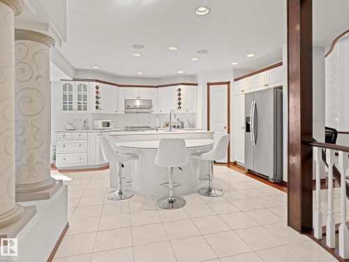 Kitchen with a kitchen bar, decorative backsplash, white cabinets, light countertops, and stainless steel refrigerator with ice dispenser - 29 Oakdale Place, St. Albert, AB - Indoor