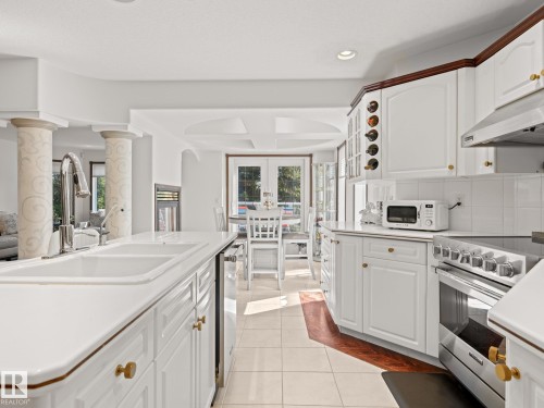 Kitchen featuring white cabinetry, appliances with stainless steel finishes, light tile patterned floors, light countertops, and backsplash - 29 Oakdale Place, St. Albert, AB - Indoor Photo Showing Kitchen