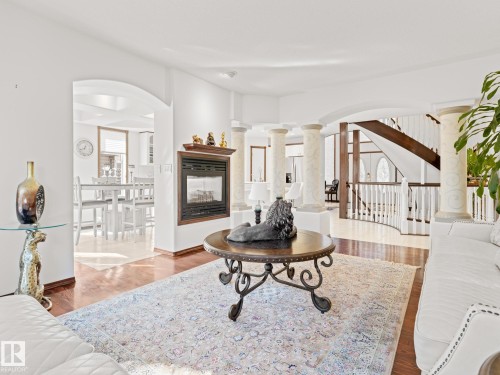 Living area with arched walkways, wood finished floors, and decorative columns - 29 Oakdale Place, St. Albert, AB - Indoor Photo Showing Living Room With Fireplace