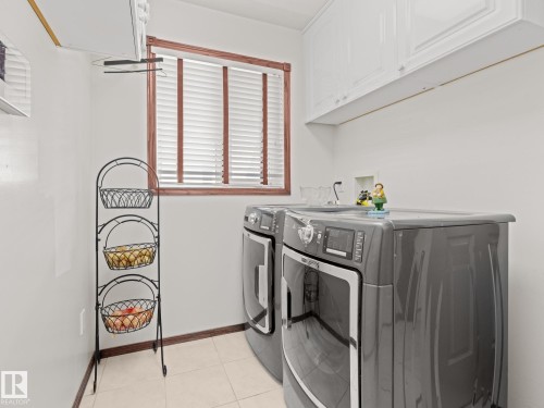 Washroom with light tile patterned floors, separate washer and dryer, and cabinet space - 29 Oakdale Place, St. Albert, AB - Indoor Photo Showing Laundry Room