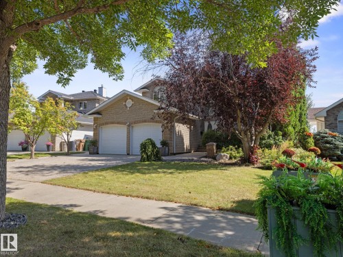 View of property hidden behind natural elements with brick siding, driveway, a front lawn, and a garage - 29 Oakdale Place, St. Albert, AB - Outdoor