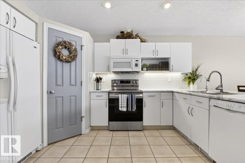 The kitchen features white cabinetry, a tiled backsplash, and a stainless steel oven - 3518 18 Street, Edmonton, AB - Indoor Photo Showing Kitchen