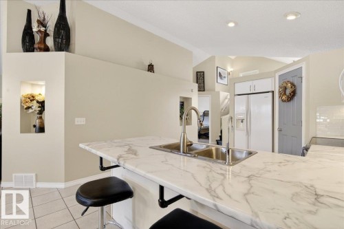 Kitchen with white marble-patterned countertops, a double basin sink with a gooseneck faucet, and white tile flooring - 3518 18 Street, Edmonton, AB - Indoor Photo Showing Kitchen With Double Sink