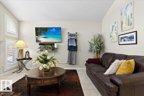 The living area features a vaulted ceiling, tiled flooring, and a large window with white louvered shutters - 3518 18 Street, Edmonton, AB - Indoor Photo Showing Living Room