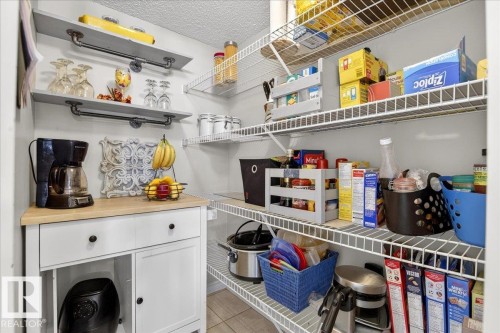 This property features a pantry with white wire shelving, a white cabinet with drawers and a light wood countertop, and two wall-mounted shelves with pipe-style hangers - 3518 18 Street, Edmonton, AB - Indoor
