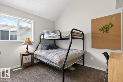 Bedroom with a window providing natural light, textured carpet flooring, and light-colored walls - 3518 18 Street, Edmonton, AB - Indoor Photo Showing Bedroom