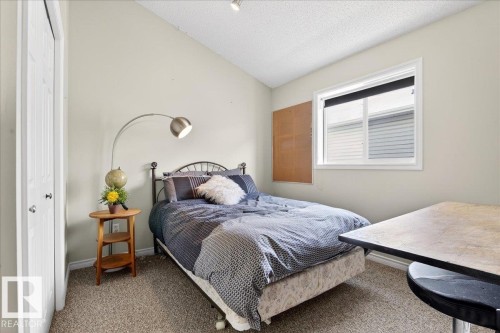 This room features neutral-toned walls, a textured carpet, and a window providing natural light - 3518 18 Street, Edmonton, AB - Indoor Photo Showing Bedroom
