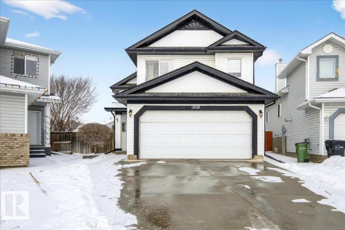 The property features a two-story exterior with white siding and dark trim, accented by a white garage door - 3518 18 Street, Edmonton, AB - Outdoor