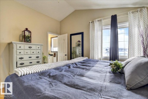 This inviting room features vaulted ceilings, light-colored walls, and a window with white window frames and drapes - 3518 18 Street, Edmonton, AB - Indoor Photo Showing Bedroom
