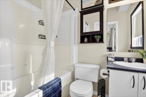 Bathroom featuring a white bathtub and shower combination, a white toilet, and a vanity with a white sink and dark countertop - 3518 18 Street, Edmonton, AB - Indoor Photo Showing Bathroom