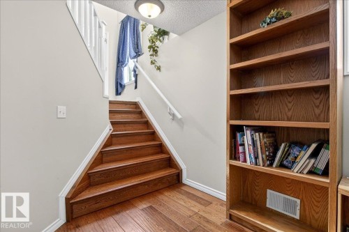 Staircase featuring hardwood treads and white risers, complemented by a white handrail and light-colored walls - 3518 18 Street, Edmonton, AB - Indoor Photo Showing Other Room