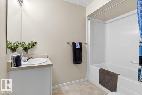 The bathroom features a vanity with an integrated sink and mirror, as well as a bathtub with a shower kit - 3518 18 Street, Edmonton, AB - Indoor Photo Showing Bathroom