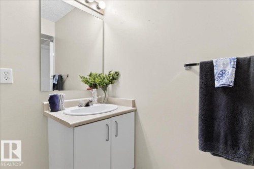 The bathroom features a vanity with a white cabinet, an integrated sink, and a mirror above - 3518 18 Street, Edmonton, AB - Indoor Photo Showing Bathroom