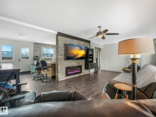 Living space featuring wood-finish flooring and a stone-clad accent wall with an integrated electric fireplace - 7607 70 Avenue, Edmonton, AB 