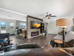 Living space featuring wood-finish flooring and a stone-clad accent wall with an integrated electric fireplace - 