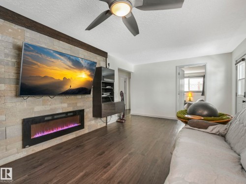 Living area featuring a stone accent wall with an integrated electric fireplace - 7607 70 Avenue, Edmonton, AB 