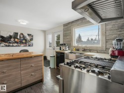 Kitchen featuring a stainless steel range with a griddle, a large window with stone-look surround, a stainless steel double basin sink. - 