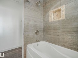 Bathtub with textured gray tile surround - 
