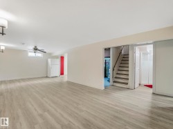 Spacious basement living room with recessed lighting, a ceiling fan, and a built-in staircase - 