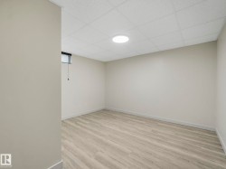 Spacious room featuring light-toned walls,  a drop ceiling, recessed lighting, and a small window with blinds - 
