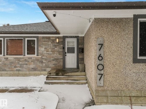 Exterior featuring stone veneer siding, textured stucco, and a white entry door - 7607 70 Avenue, Edmonton, AB 