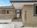 Exterior featuring stone veneer siding, textured stucco, and a white entry door - 7607 70 Avenue, Edmonton, AB 